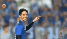 a man in a blue soccer jersey is pointing at something in the distance .