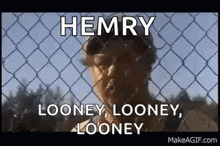 a man is standing behind a chain link fence with a beard and sunglasses .
