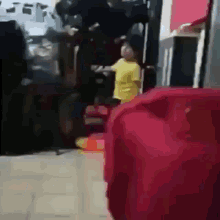 a blurry picture of a person in a yellow shirt standing in front of a red item .