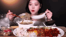 a woman is eating a plate of food with chopsticks and a ladle