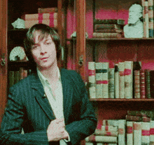 a man in a suit is standing in front of a book shelf