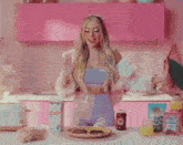 a woman is singing into a microphone while cooking in a pink kitchen .