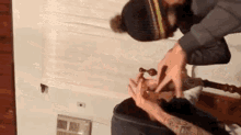 a man with a tattoo on his arm is holding a woman 's hand while laying on a bed .