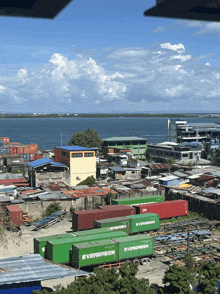a row of green evergreen shipping containers are parked in front of a body of water