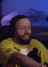 a man with a beard wearing headphones and a yellow shirt with a w logo on the sleeve