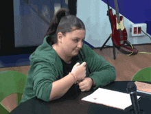 a woman in a green jacket sits at a table
