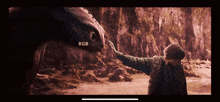 a screen shows a man touching the nose of a dragon with the letters rgb visible