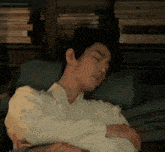 a man in a white shirt is sleeping on a bed