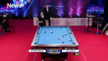a pool table with a woman holding a cue in front of a sign that says hot news