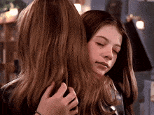 two girls hugging each other with their eyes closed and their hair visible