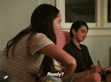 a man and a woman are sitting on a couch and the woman says " ready "