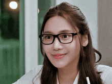 a woman wearing glasses and a white shirt smiles