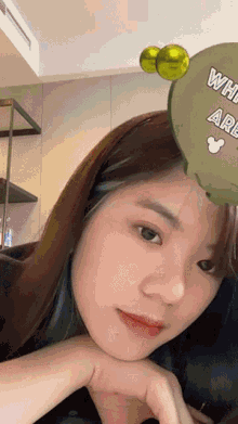 a close up of a woman 's face with a green balloon that says " what are you "