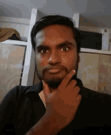 a man with a beard is making a funny face with his hand on his chin