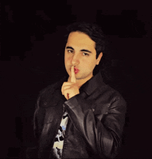 a young man wearing a black leather jacket is pointing at something