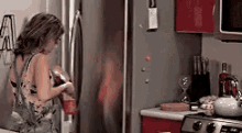 a woman is standing in a kitchen with a bottle of wine in her hand .
