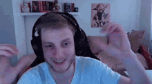 a man wearing headphones and a white shirt is sitting in front of a poster of yoda .