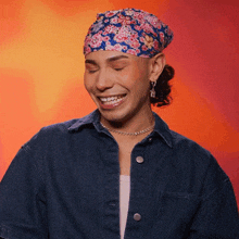 a woman wearing a headband and a denim shirt smiles