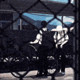 two boys are standing next to bicycles behind a chain link fence .