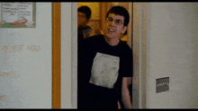 a man wearing a black shirt with a metallica logo on it is standing in a doorway