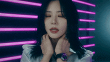 a woman wearing a watch has her eyes closed in front of a neon wall