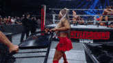 a woman in a red skirt and boots is standing in a wrestling ring .
