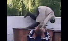 a man is doing a trick on another man 's head while standing on a table .