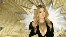 a woman with a very plunging neckline is standing in front of a gold background .