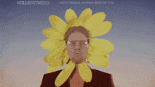 a man wearing glasses and a yellow flower on his head says kollektiv