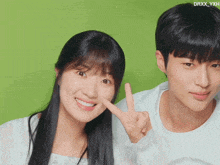 a man and a woman are posing for a picture and the woman is giving the peace sign