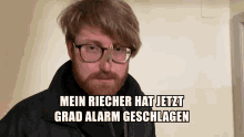 a bearded man wearing glasses and a black jacket says mein richer hat jetzt grad alarm geschlagen