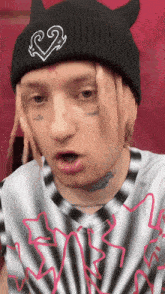 a man with dreadlocks wearing a black beanie and a striped shirt