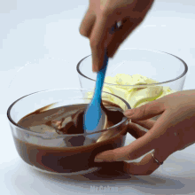 a person is mixing a chocolate sauce in a glass bowl