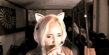 a woman wearing a cat ear headset is eating a sandwich