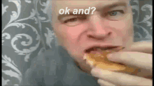 a man is eating a hamburger with the words ok and written on the bottom