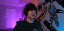 a man wearing headphones and a black shirt is standing in front of a microphone in a room .