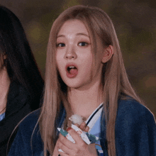 a girl with blonde hair is holding something in her hand and making a surprised look on her face
