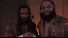 a man with dreadlocks and a beard is smiling next to another man
