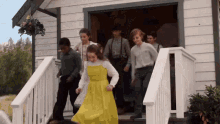 a girl in a yellow dress is walking down the stairs of a house