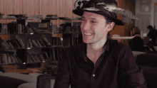 a man wearing a hat with feathers is smiling