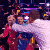 a group of people are dancing in a dark room and one of them is wearing a red dress
