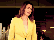 a woman in a yellow jacket stands in front of a dark room