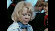 a woman with blonde hair is wearing a blue scarf around her neck