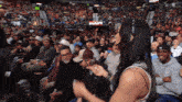 a woman stands in front of a crowd at a wrestling event with a sign that says ' raw ' on it