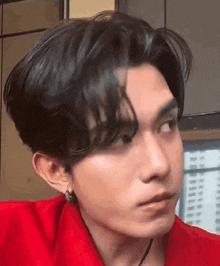 a close up of a man 's face with a red shirt and earrings .