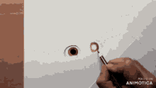 a person is drawing an eye with a brush and the words made in animonica are visible