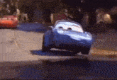 a blue car from cars is driving down a street .