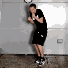 a man wearing a black shirt with the letter l on it is dancing