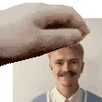 a hand is holding a man 's head in a pixelated image .