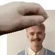 a hand is holding a man 's head in a pixelated image .
